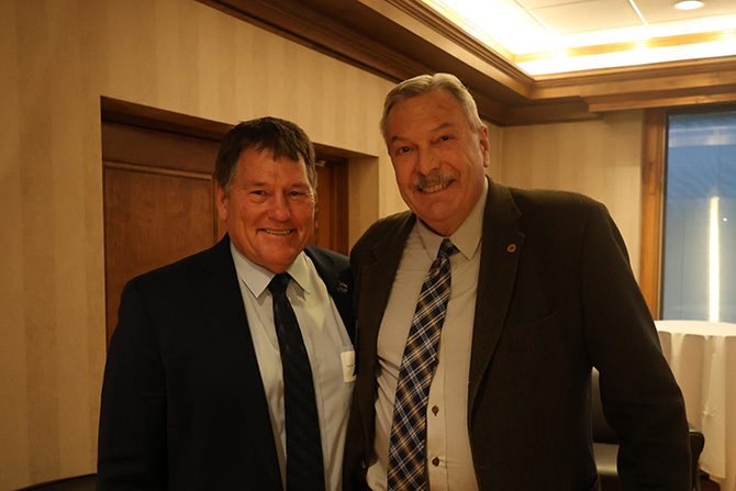 Two men in suites smile at a conference