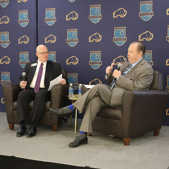 2026 BLOK Academy and Harold A. Stones Government Relations Conference; Two men in suits are seated on stage, holding microphones, against a backdrop featuring "Kansas Bankers" logos and buffalo images.